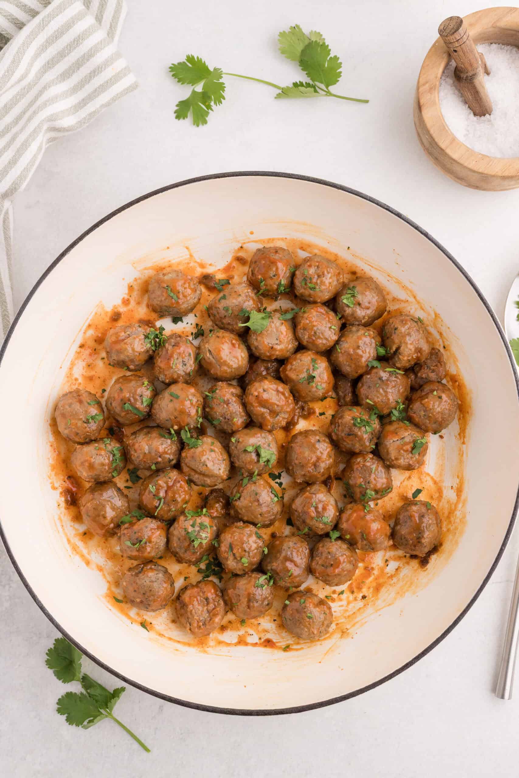 Sriracha meatballs garnished with fresh cilantro in a skillet.