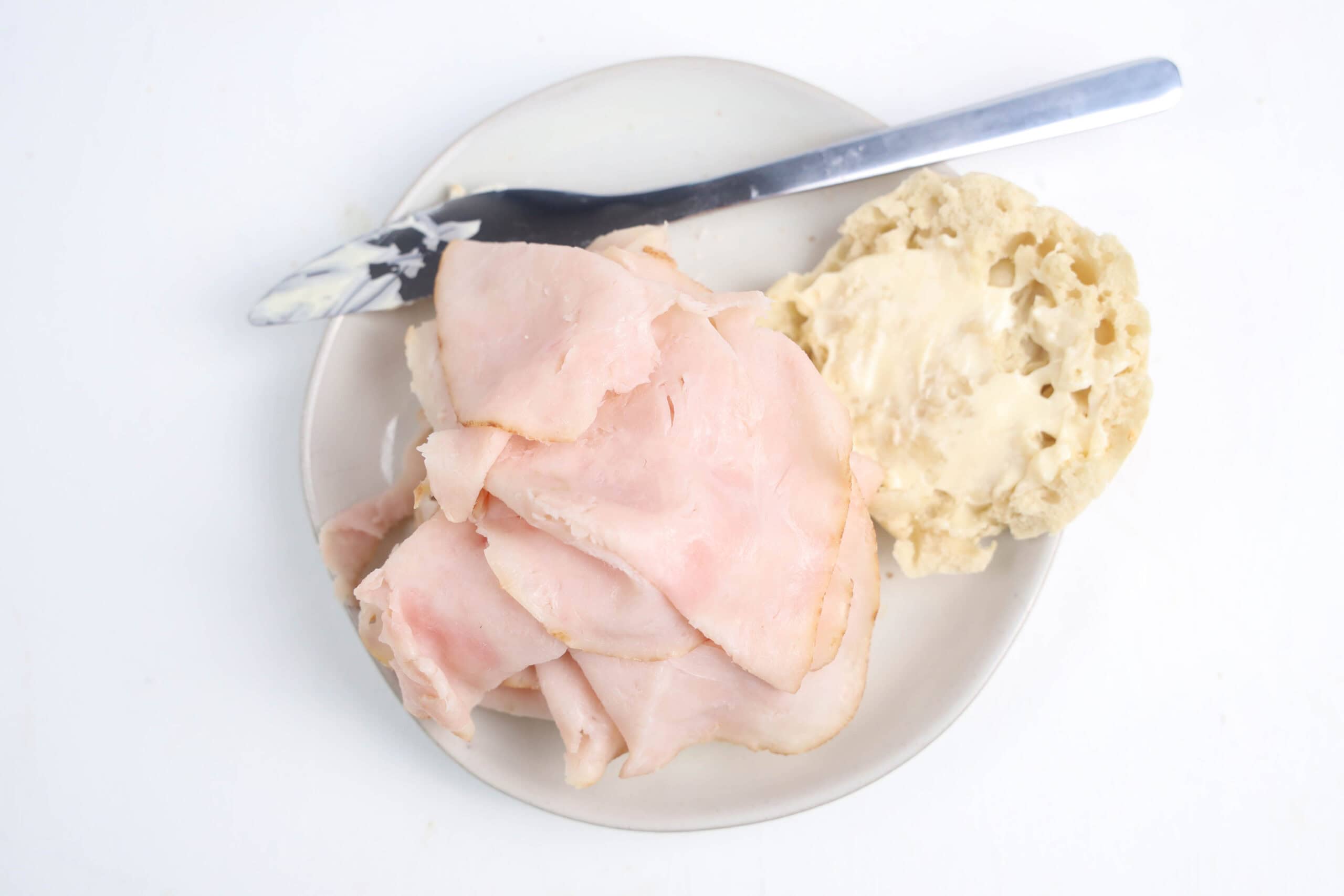 Sliced turkey layered on the bottom half of an English muffin.