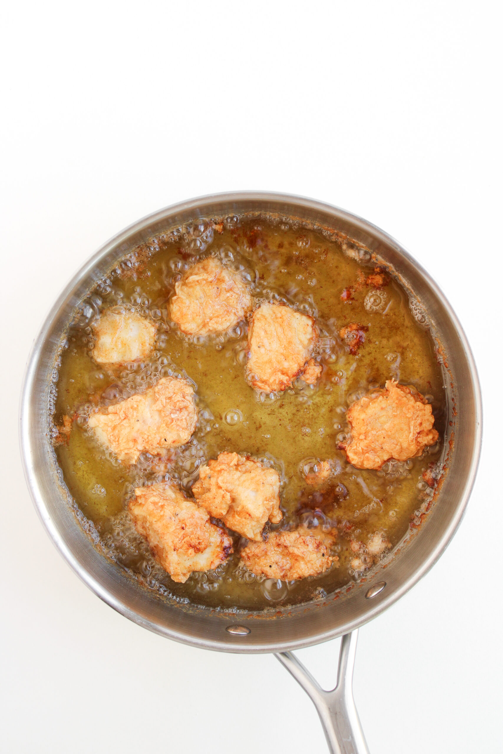 Coated chicken pieces frying in hot oil until golden.