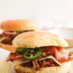 A BBQ cowboy sloppy joe sandwich topped with pepper jack cheese, bacon, jalapeños, and crispy onions.