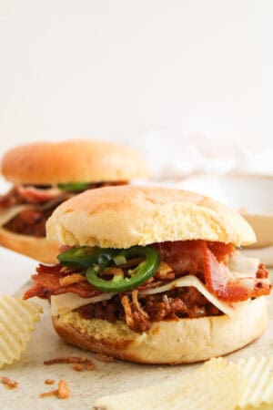 A BBQ cowboy sloppy joe sandwich topped with pepper jack cheese, bacon, jalapeños, and crispy onions.