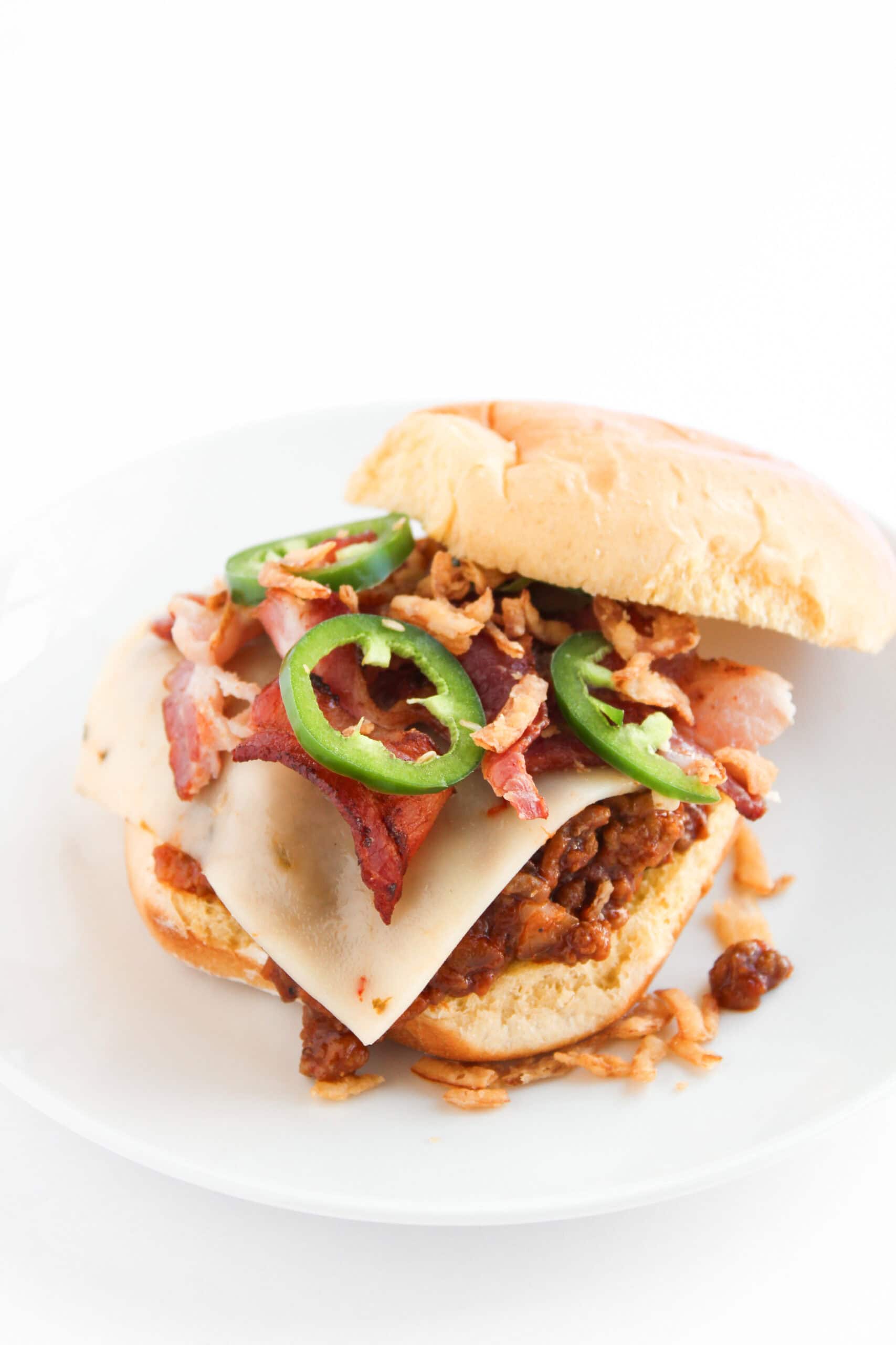 A BBQ sloppy joe sandwich topped with cheese, bacon, jalapeños, and crispy onions.