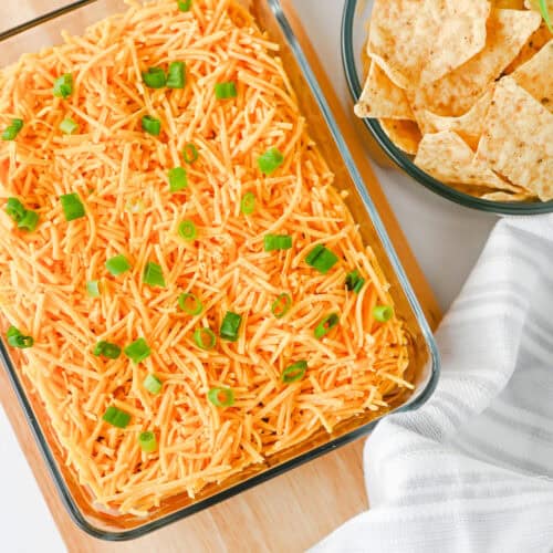 High protein nacho dip topped with cheddar cheese and green onions, served with tortilla chips.