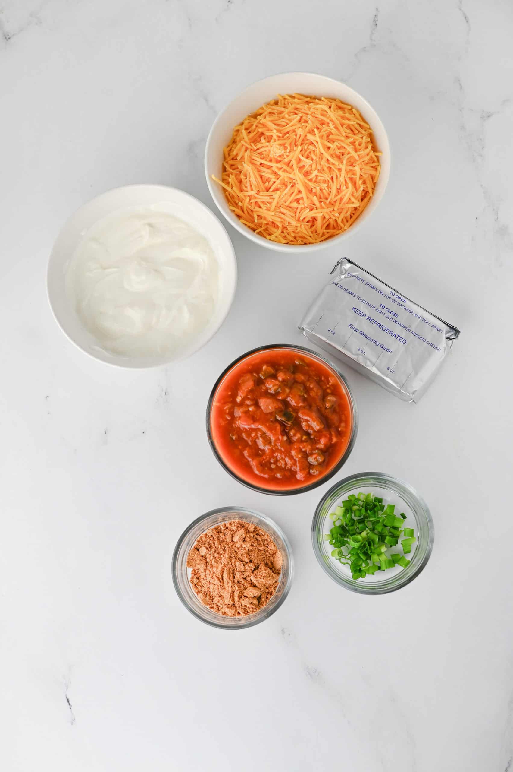 Greek yogurt, cream cheese, taco seasoning, salsa, cheddar cheese, and green onions.