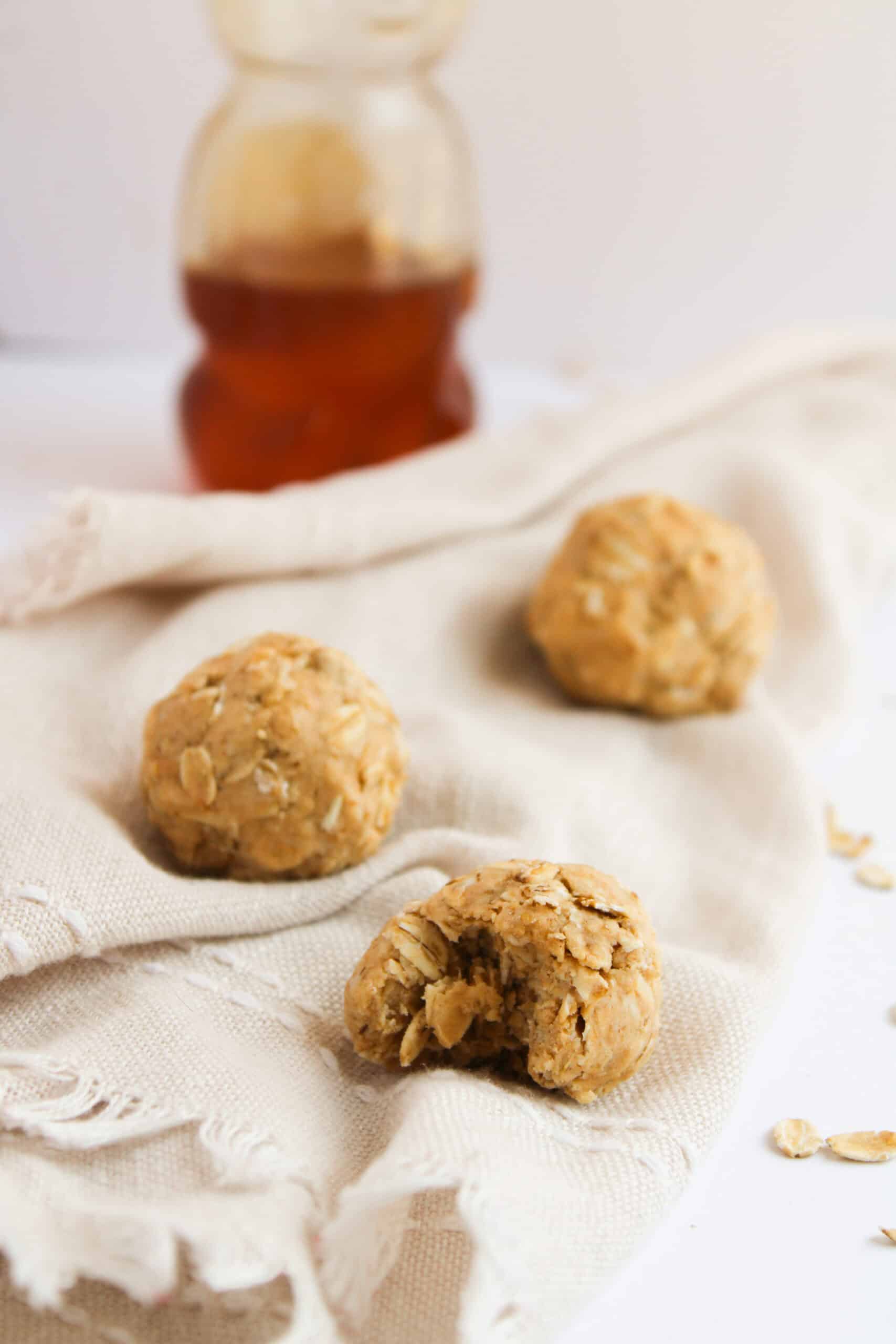 A peanut butter oat protein bite with a bite taken out beside honey.