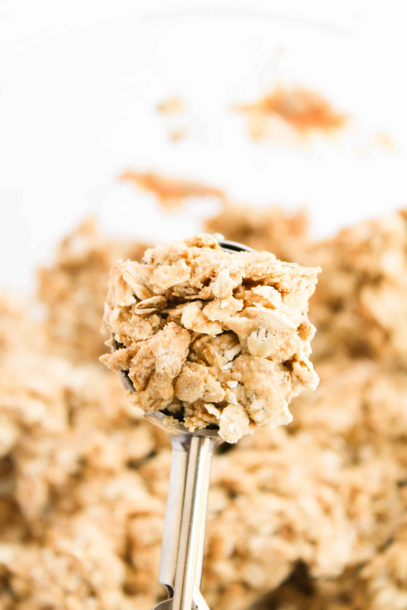 A cookie scoop holding chilled peanut butter oat protein bite mixture.
