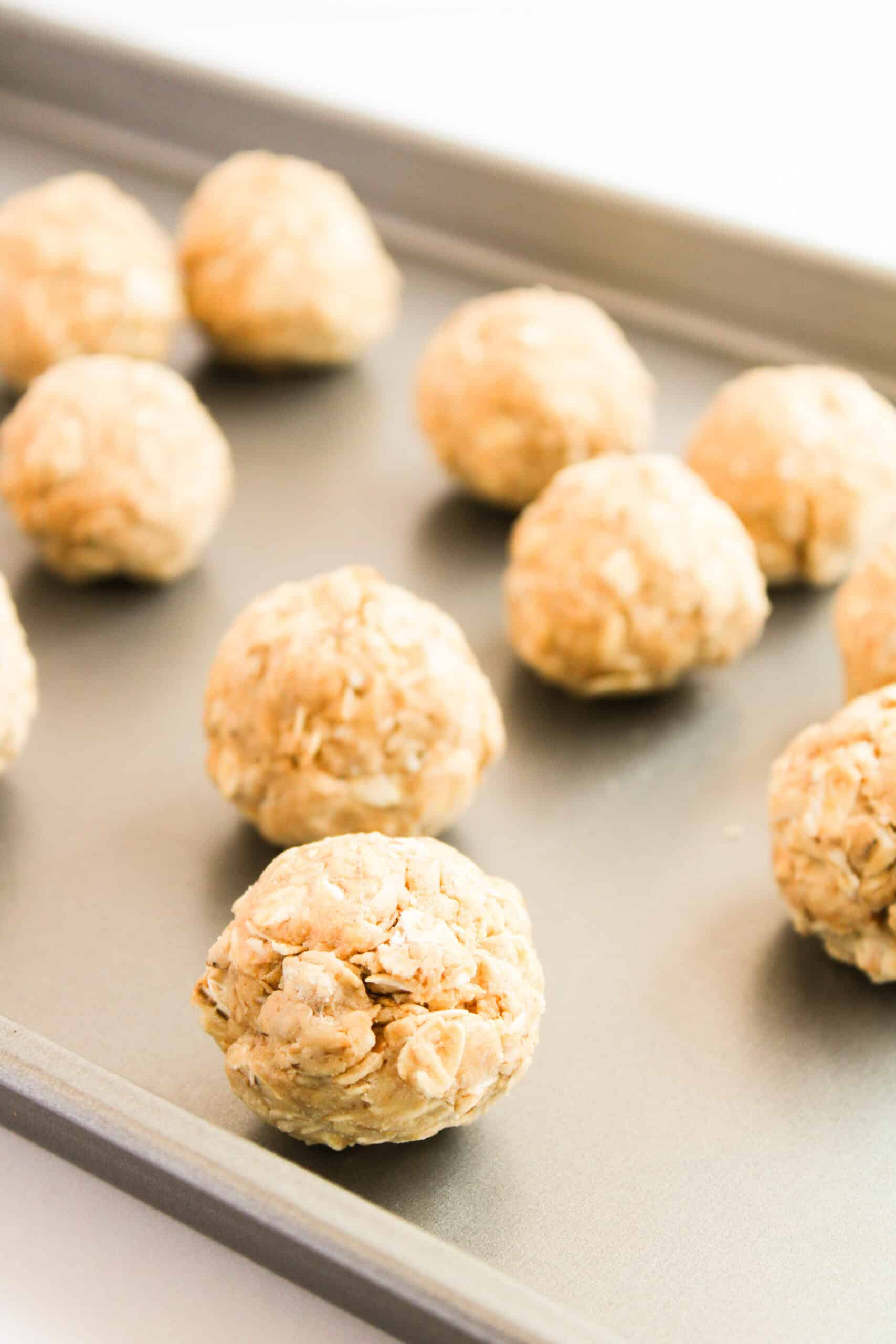 Peanut butter and oat protein bites rolled into balls on a baking sheet.