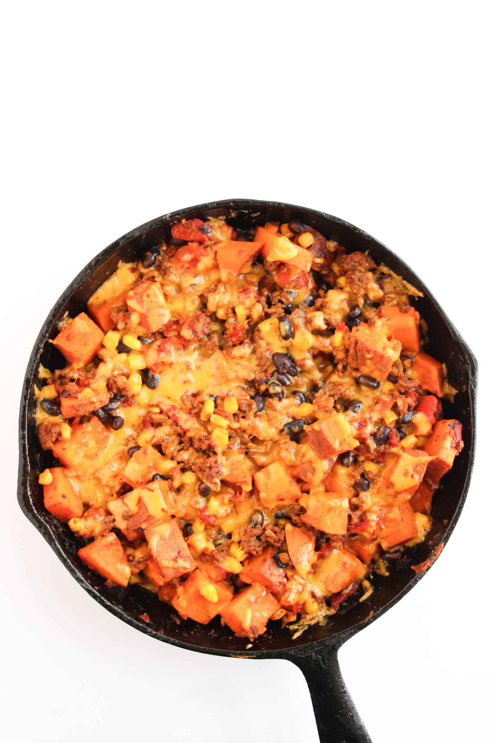 Sweet potato taco skillet topped with melted cheddar cheese.