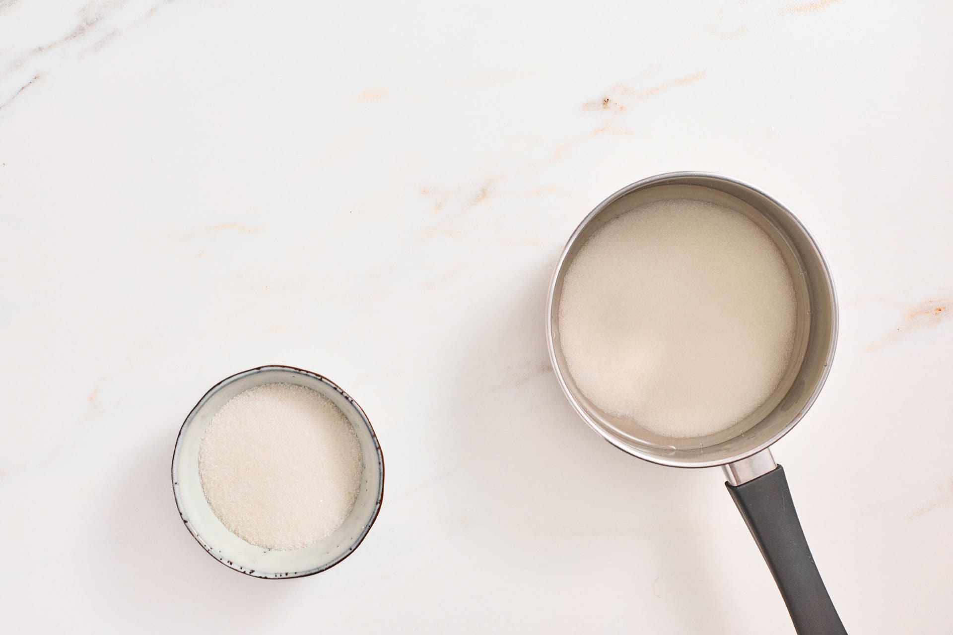 Sugar and water combined in a saucepan to make simple syrup.