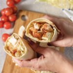 Two toasted chicken Caesar wrap halves filled with seasoned chicken, romaine, Parmesan, croutons, and Caesar dressing.