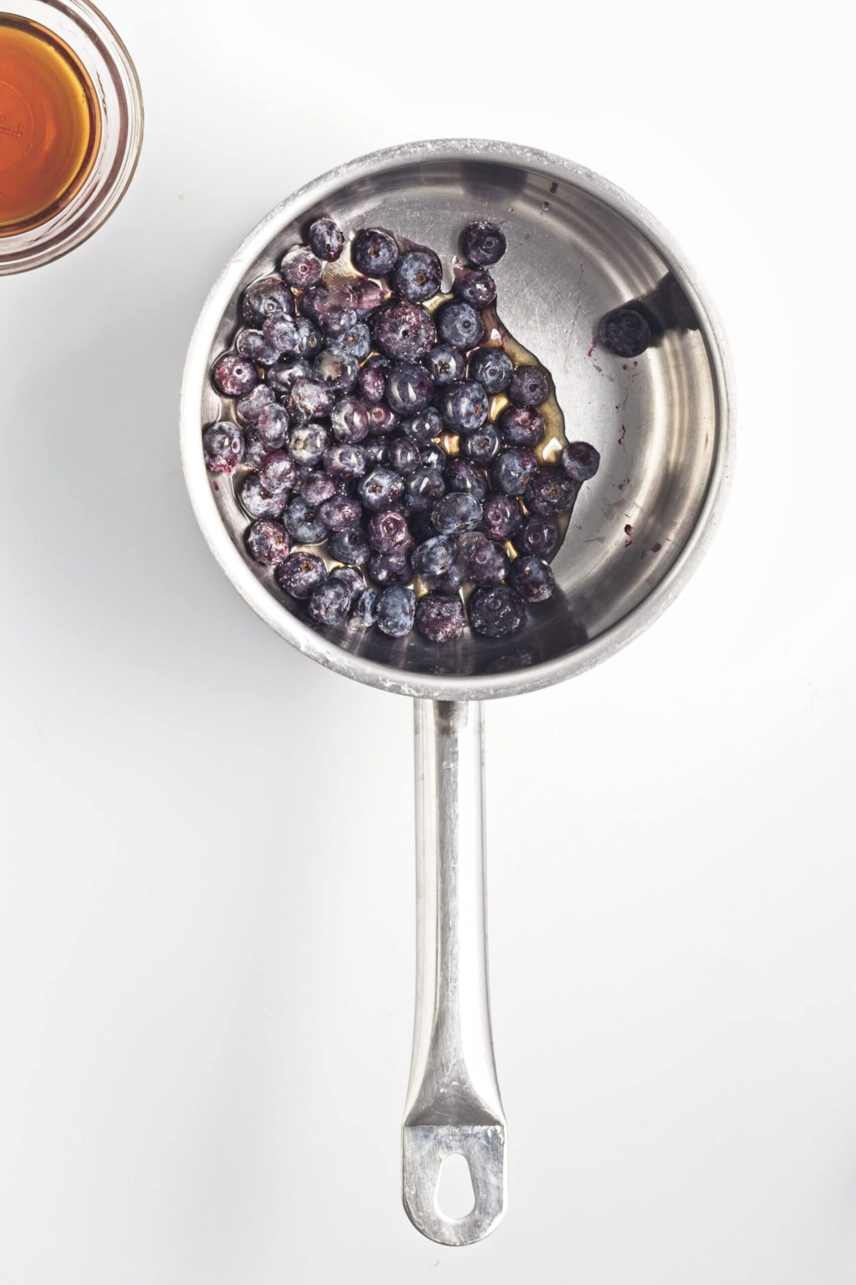 Blueberries and maple syrup combined in a saucepan for compote.