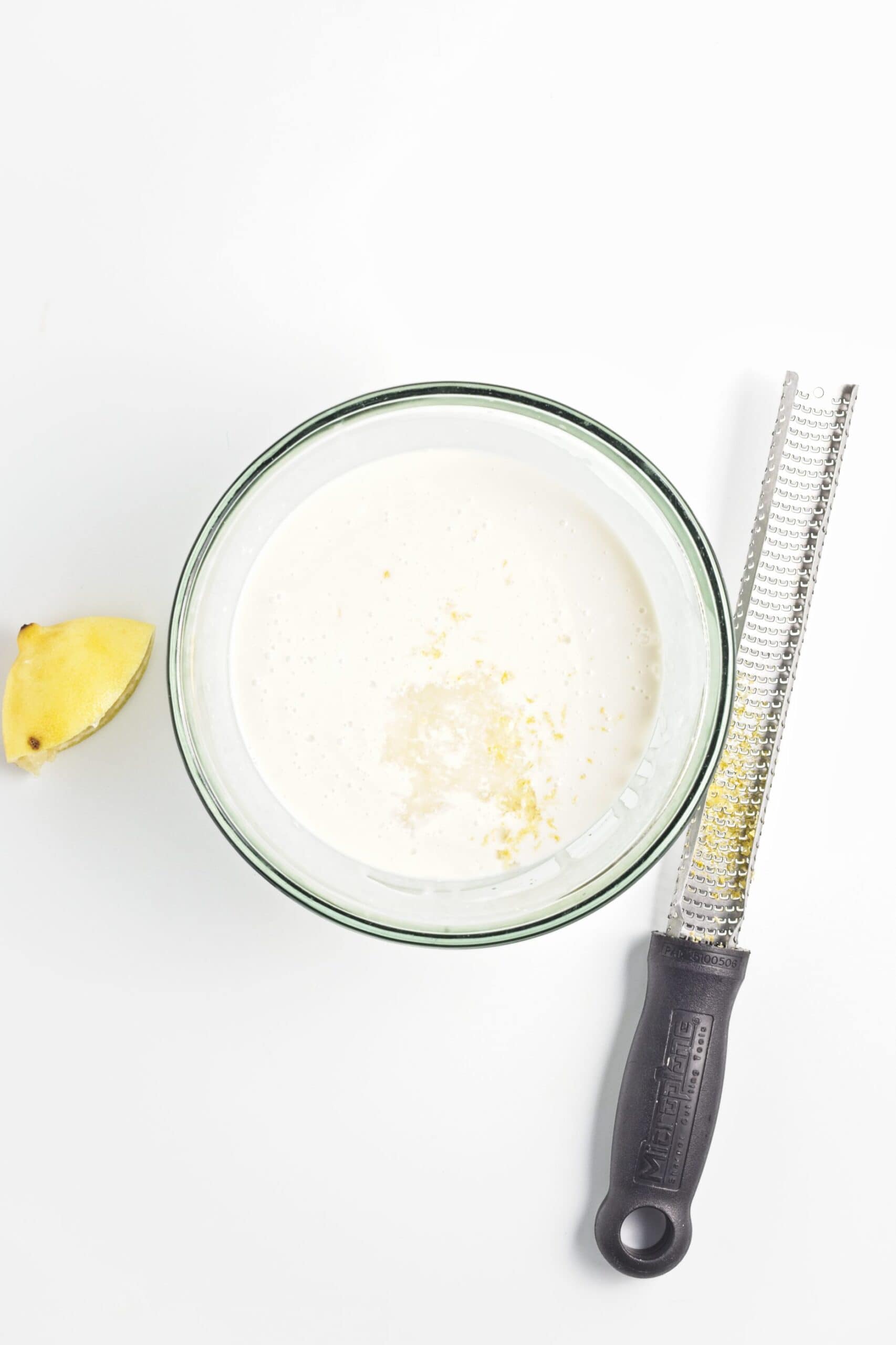 Coconut milk mixture with lemon zest in a glass bowl.