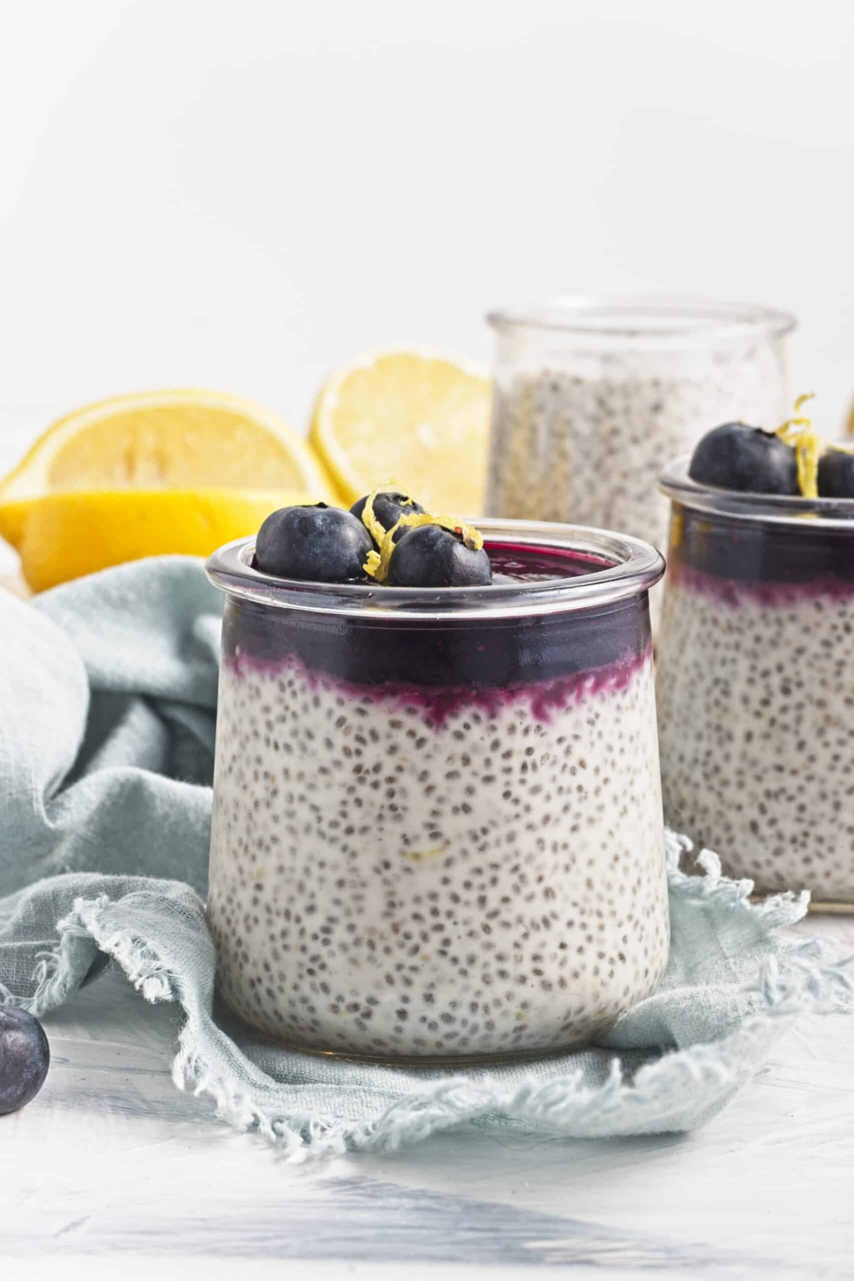 Three jars of lemon chia pudding topped with blueberry compote and fresh blueberries.
