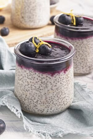 Close-up of creamy lemon chia pudding topped with blueberry compote, fresh blueberries, and lemon zest.