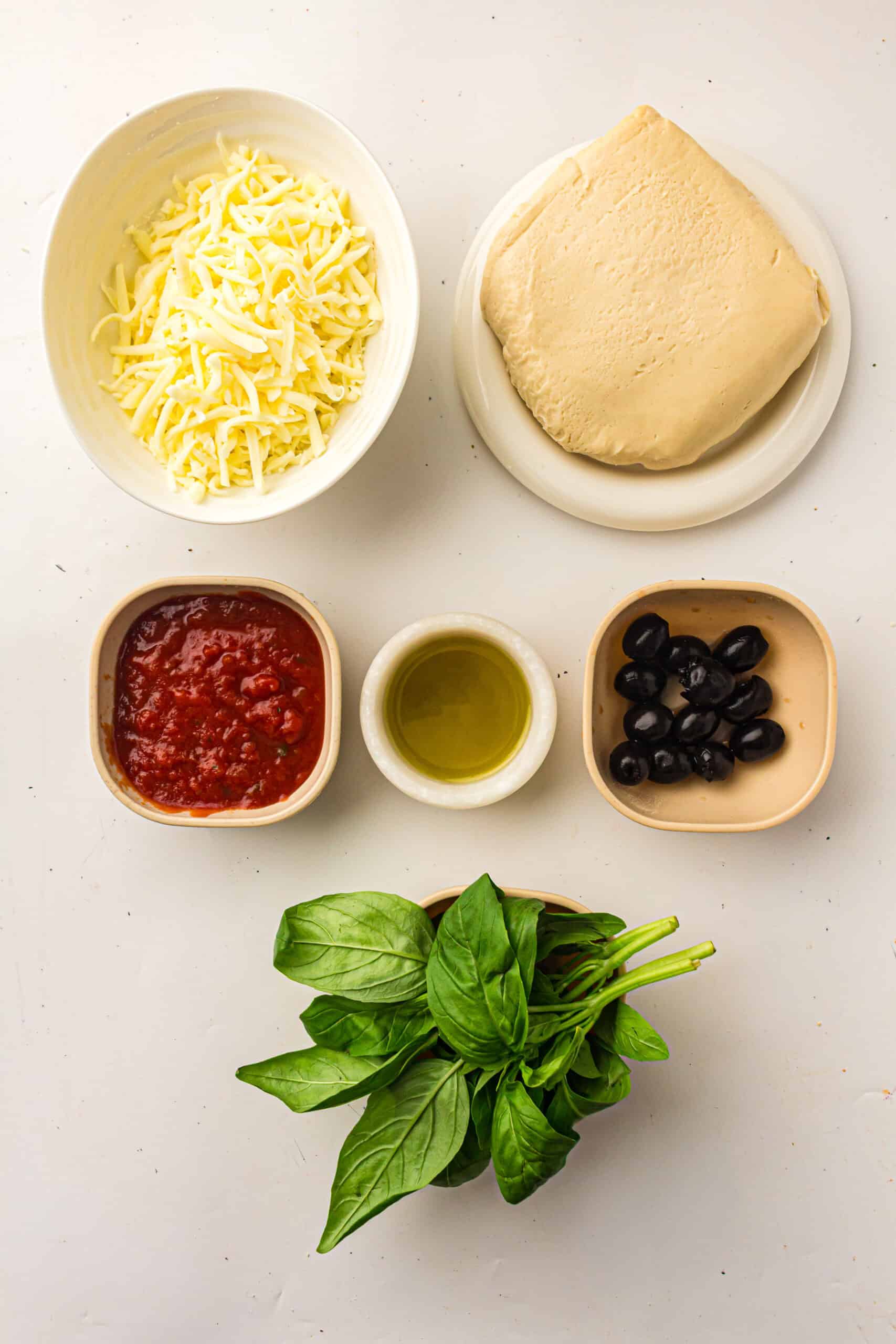 Pizza dough, mozzarella, pizza sauce, olive oil, black olives, and fresh basil for pizza muffins.