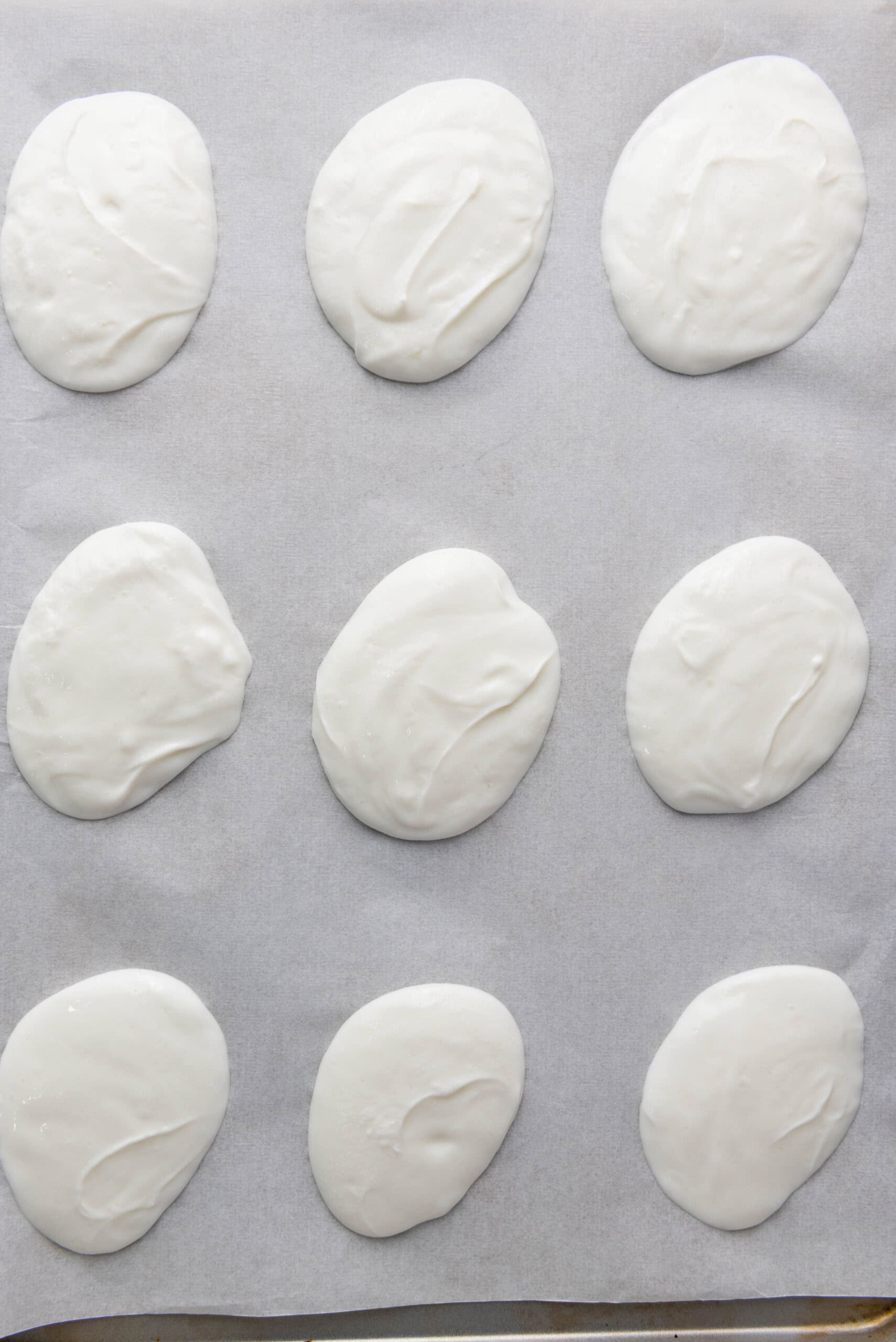 Greek yogurt spooned into small dollops on a parchment-lined baking sheet.