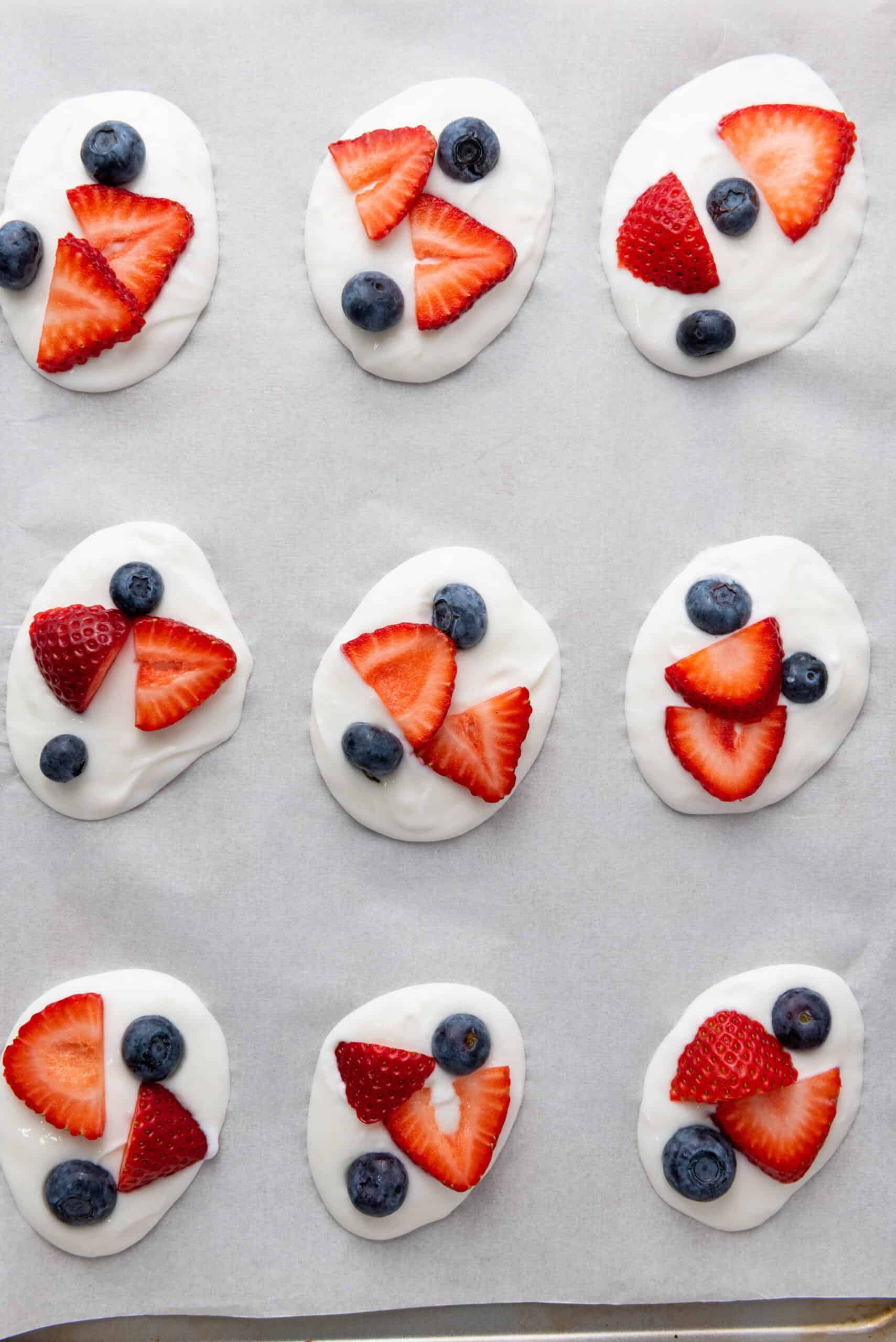 Sliced strawberries and blueberries added to yogurt dollops.