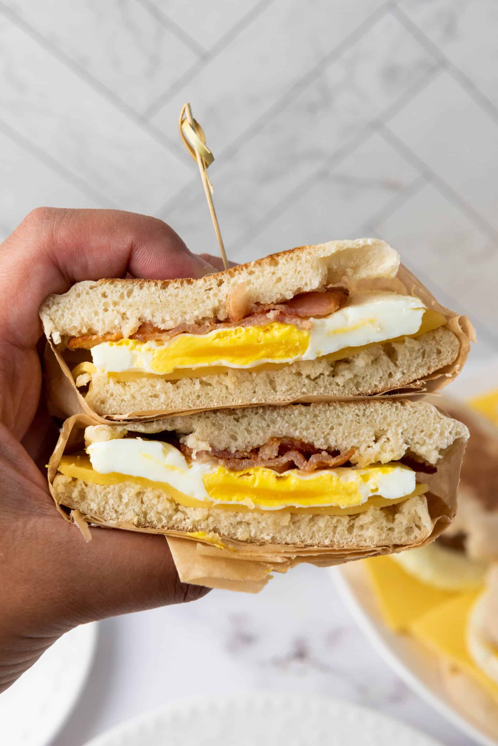 Cross-section of a bacon, egg, and cheese breakfast sandwich on an English muffin.