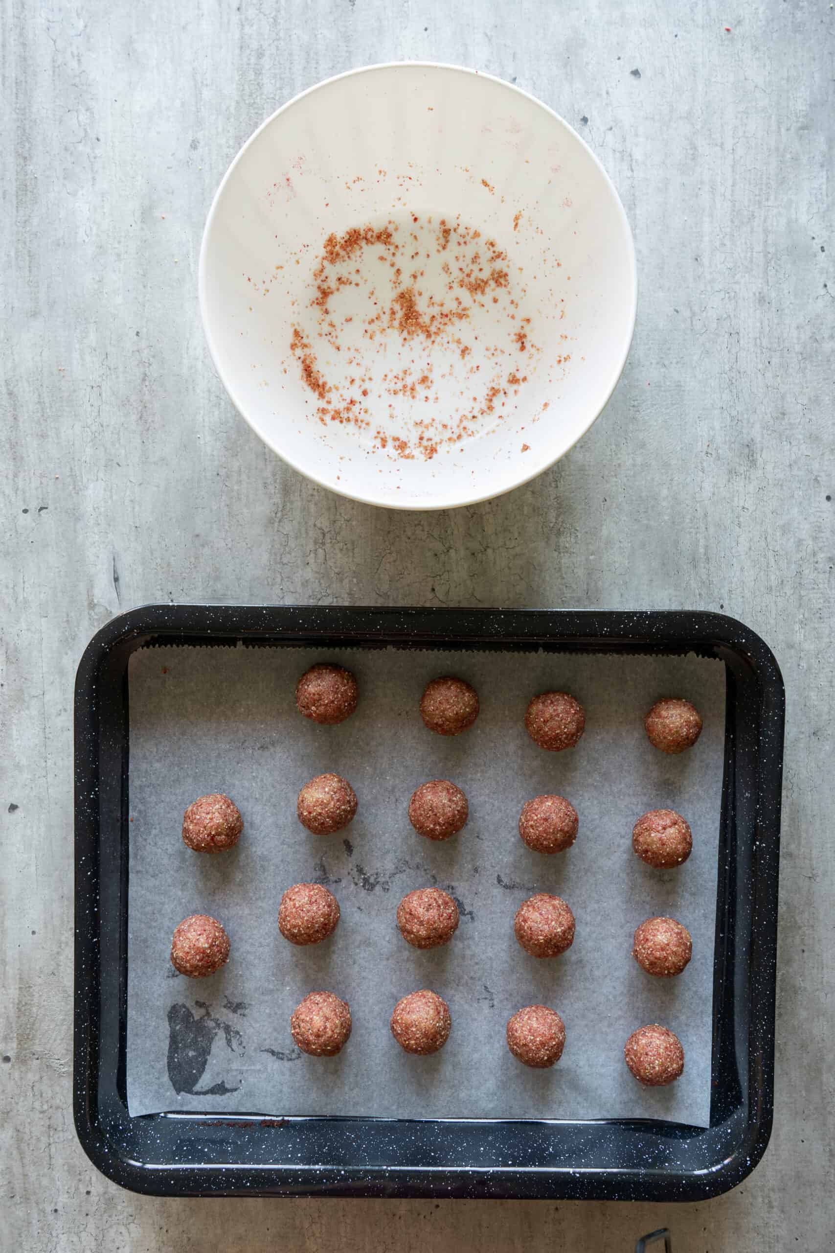 Rolled strawberry energy bites arranged on a parchment-lined tray.