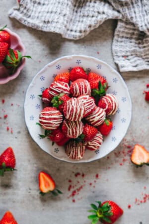 Overhead view of strawberry shortcake energy bites with white chocolate drizzle and fresh strawberries.