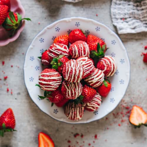 Overhead view of strawberry shortcake energy bites with white chocolate drizzle and fresh strawberries.