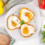 Three bell pepper egg rings garnished with parsley on a plate.