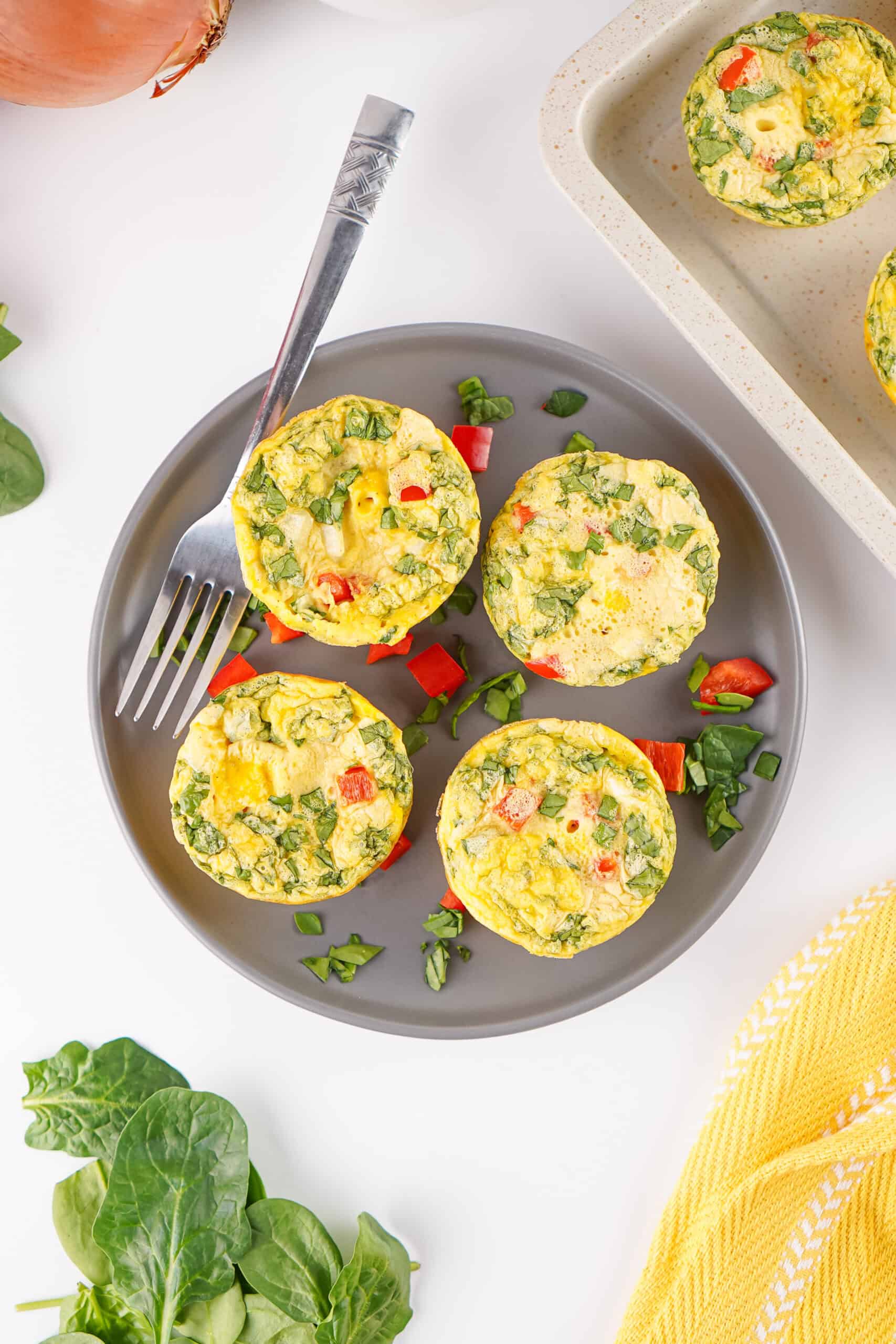 Cottage cheese egg bites with spinach, bell pepper, and onion arranged on a plate.