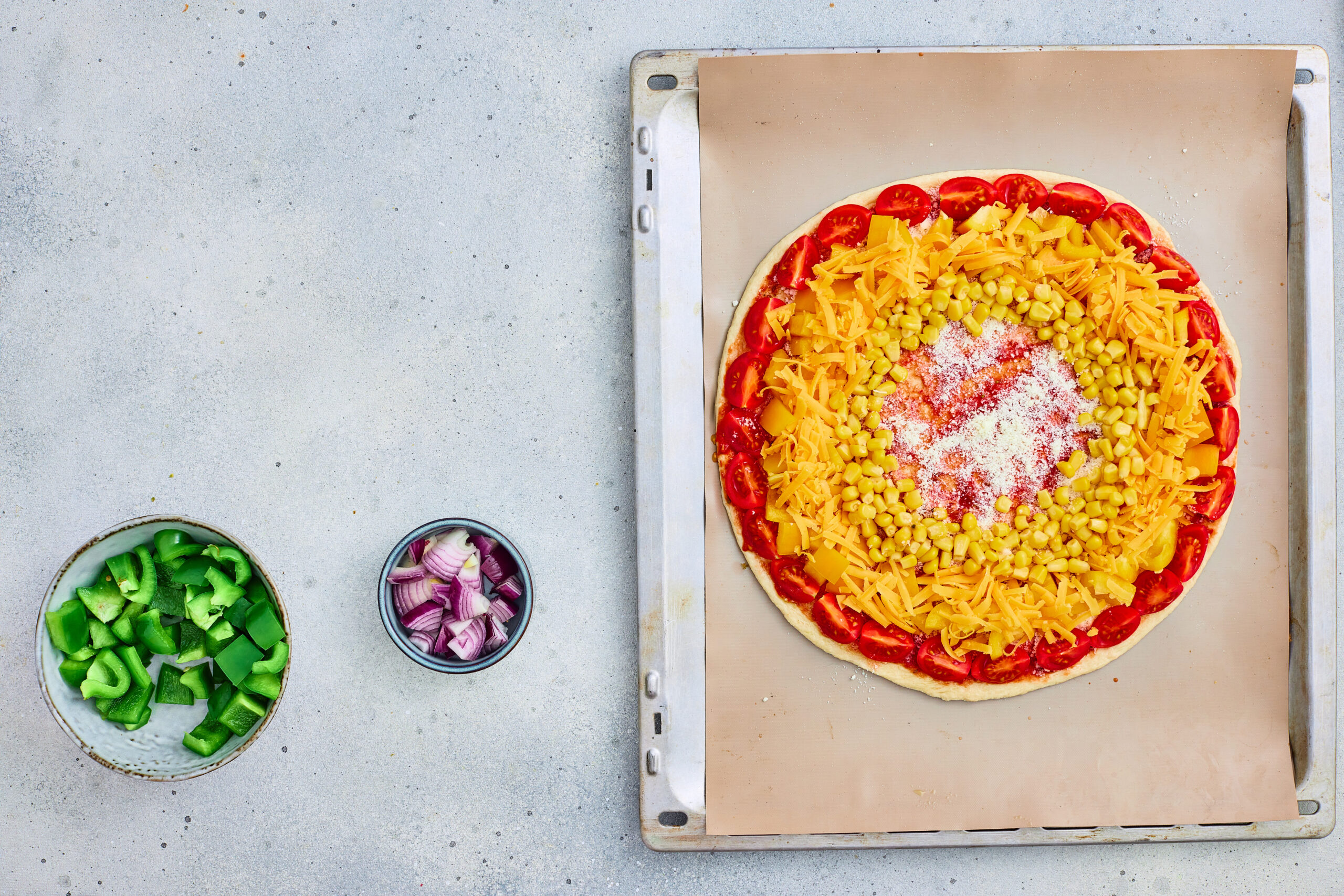 Sweet corn arranged as a yellow ring on rainbow veggie pizza.