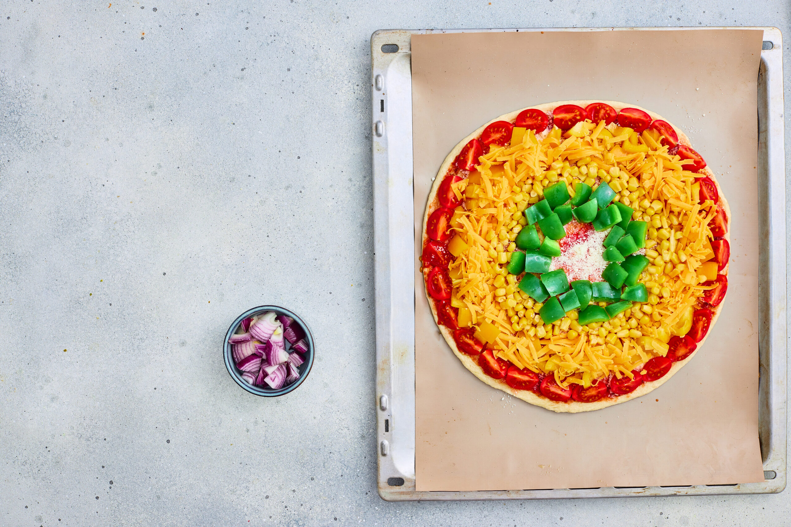 Green bell pepper arranged in a ring near the center of rainbow pizza.