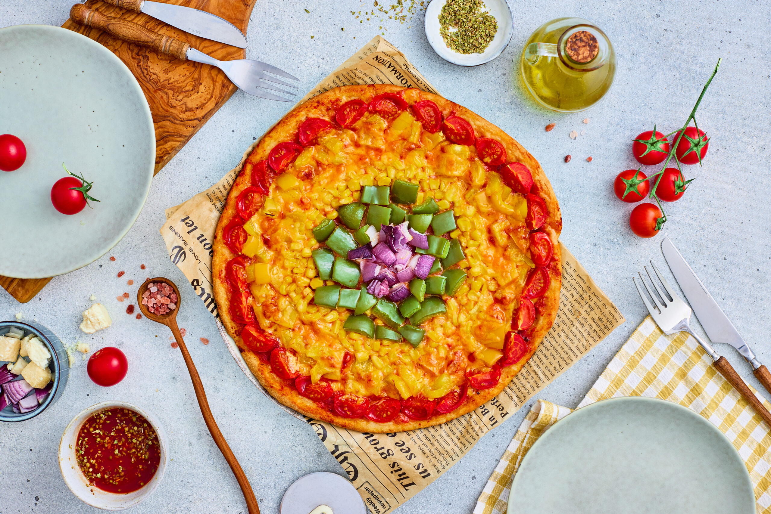 Baked rainbow wheel veggie pizza topped with colorful vegetable rings.
