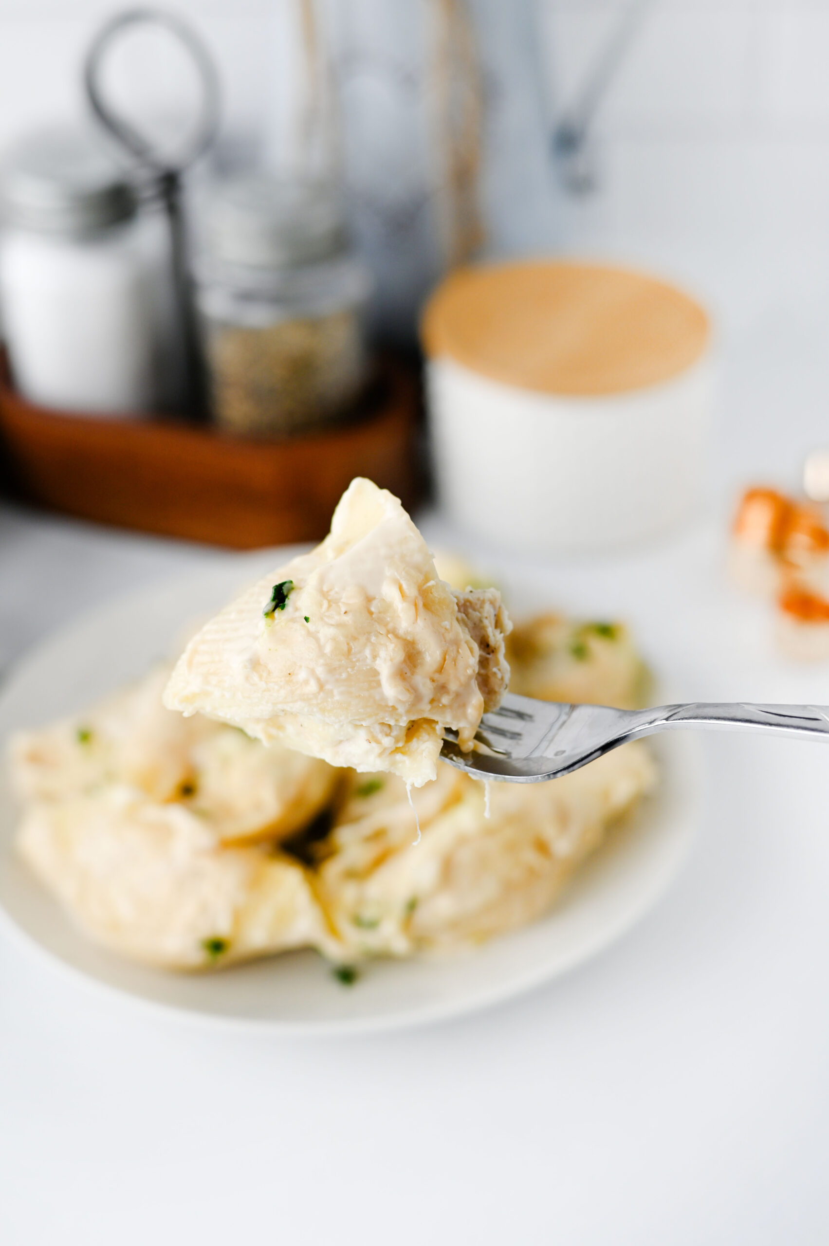 A fork holding a creamy chicken Alfredo stuffed shell.