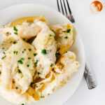 Chicken Alfredo stuffed shells served on a white plate with parsley.
