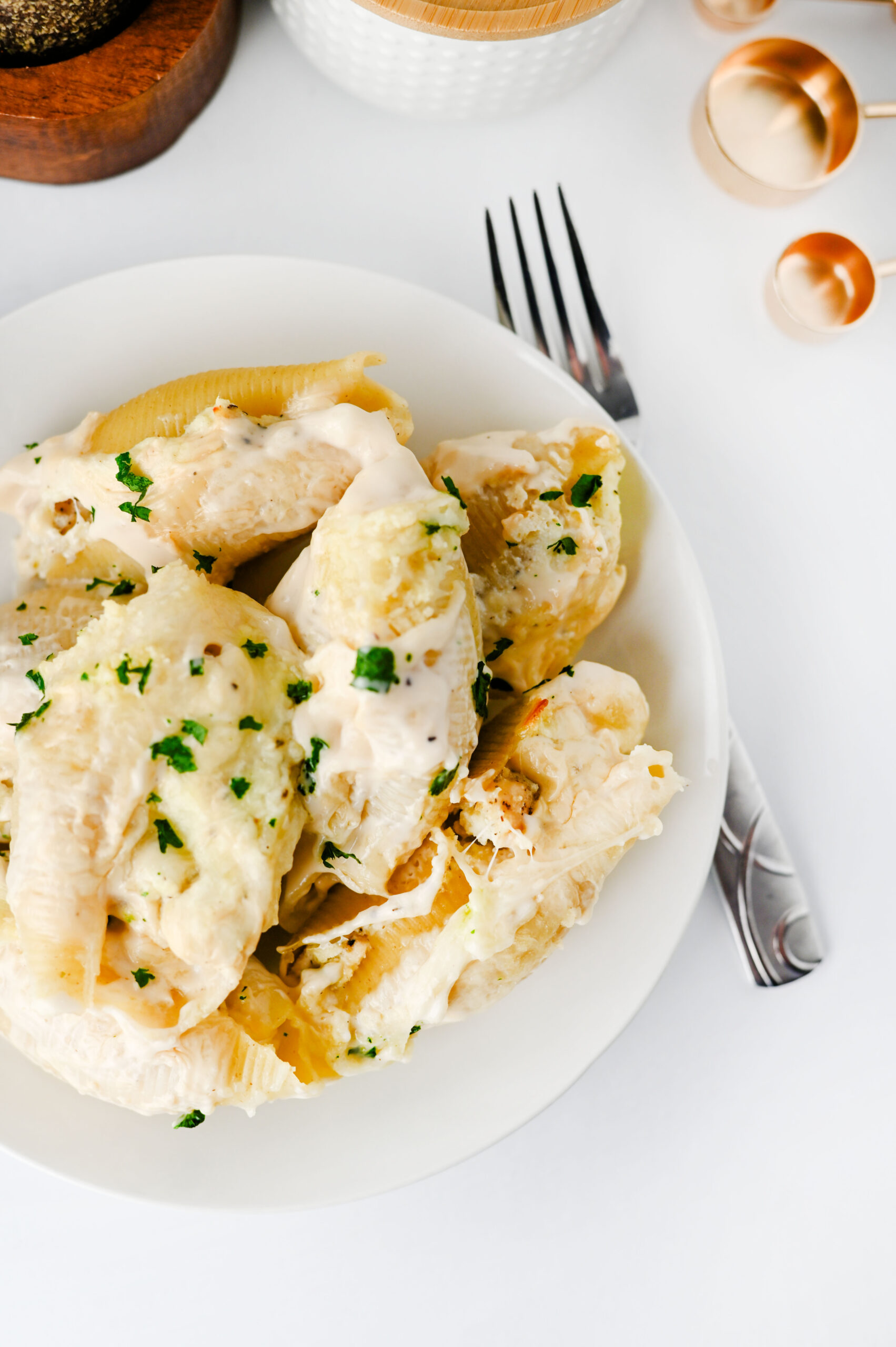 Chicken Alfredo stuffed shells served on a white plate with parsley.