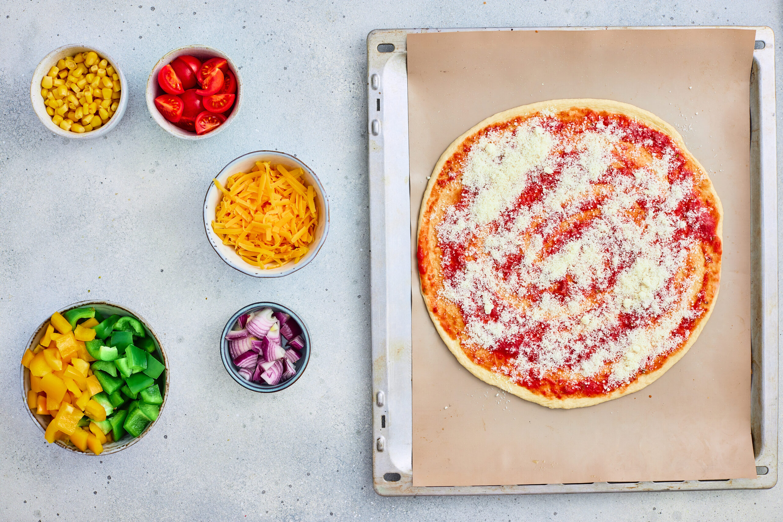 Finely grated parmesan spread over tomato sauce on pizza dough.