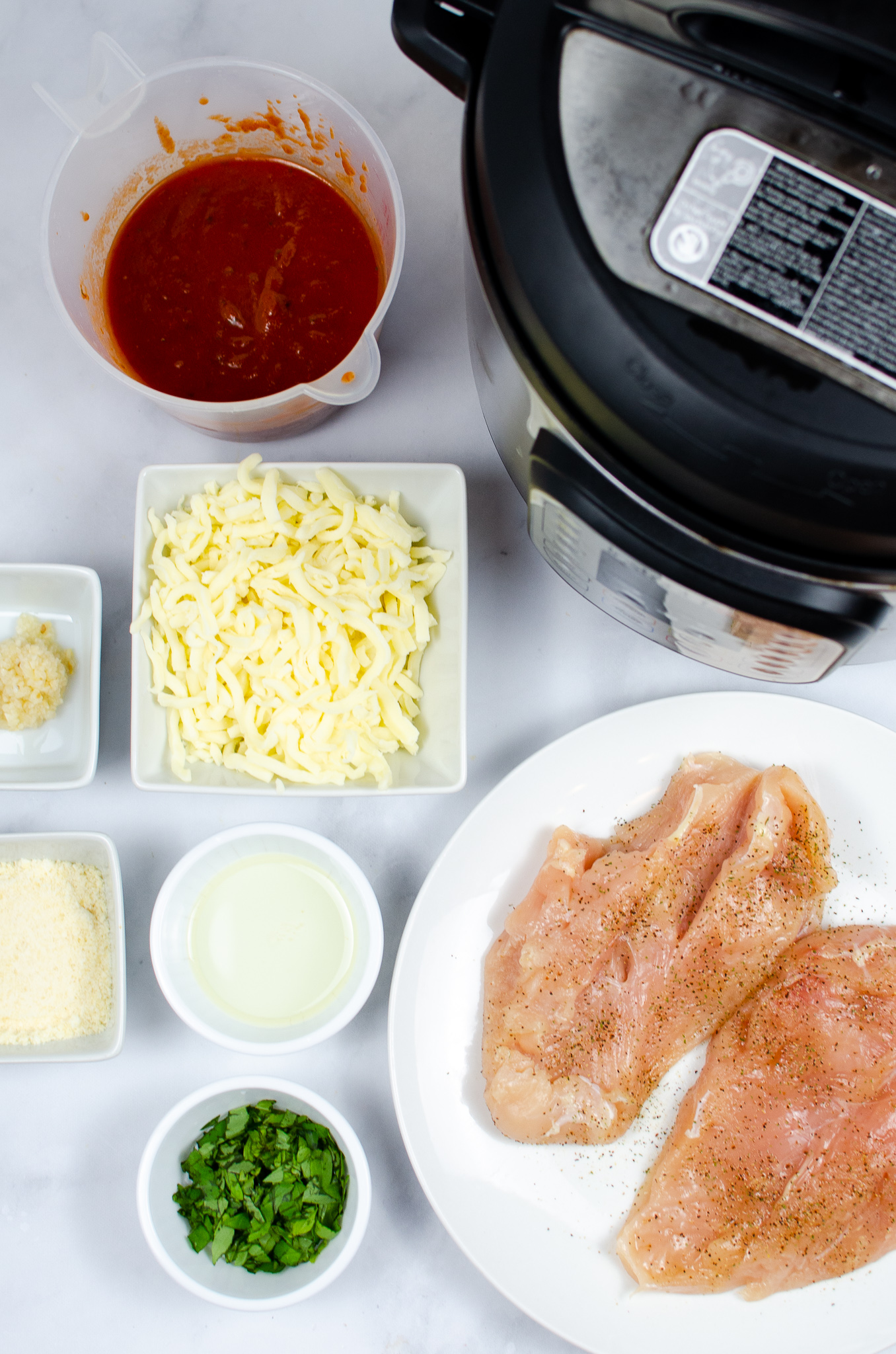 Chicken breasts, marinara, mozzarella, Parmesan, basil, garlic, olive oil, seasoning, and an Instant Pot.