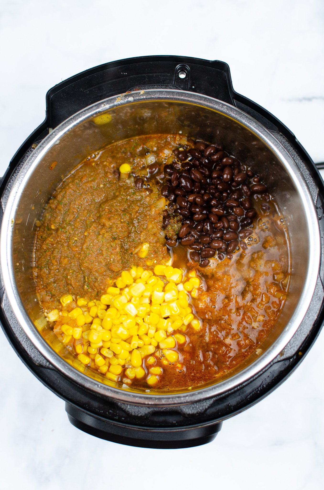 Black beans, corn, and salsa added to chicken in an Instant Pot.