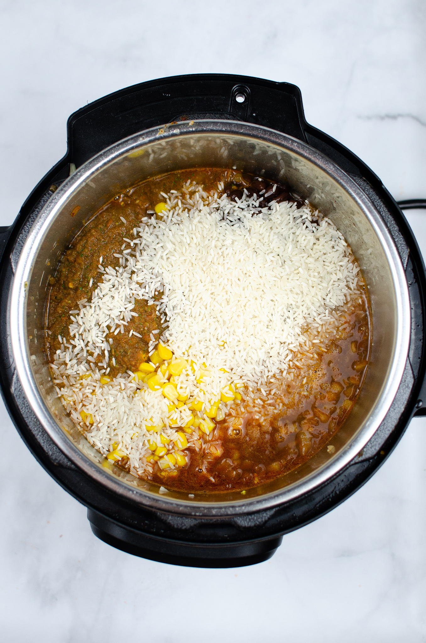 Long-grain white rice layered on top of the burrito bowl mixture before pressure cooking.
