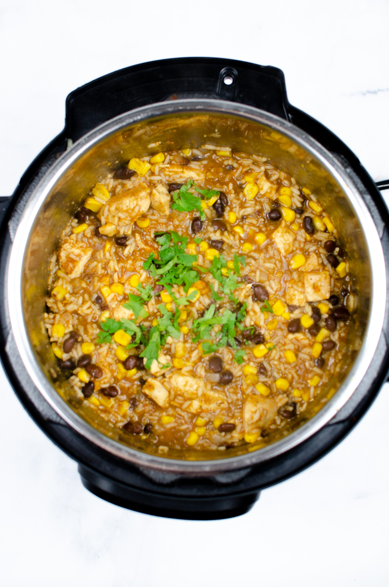 Cooked chicken burrito bowl mixture with rice, beans, corn, chicken, and cilantro in an Instant Pot.