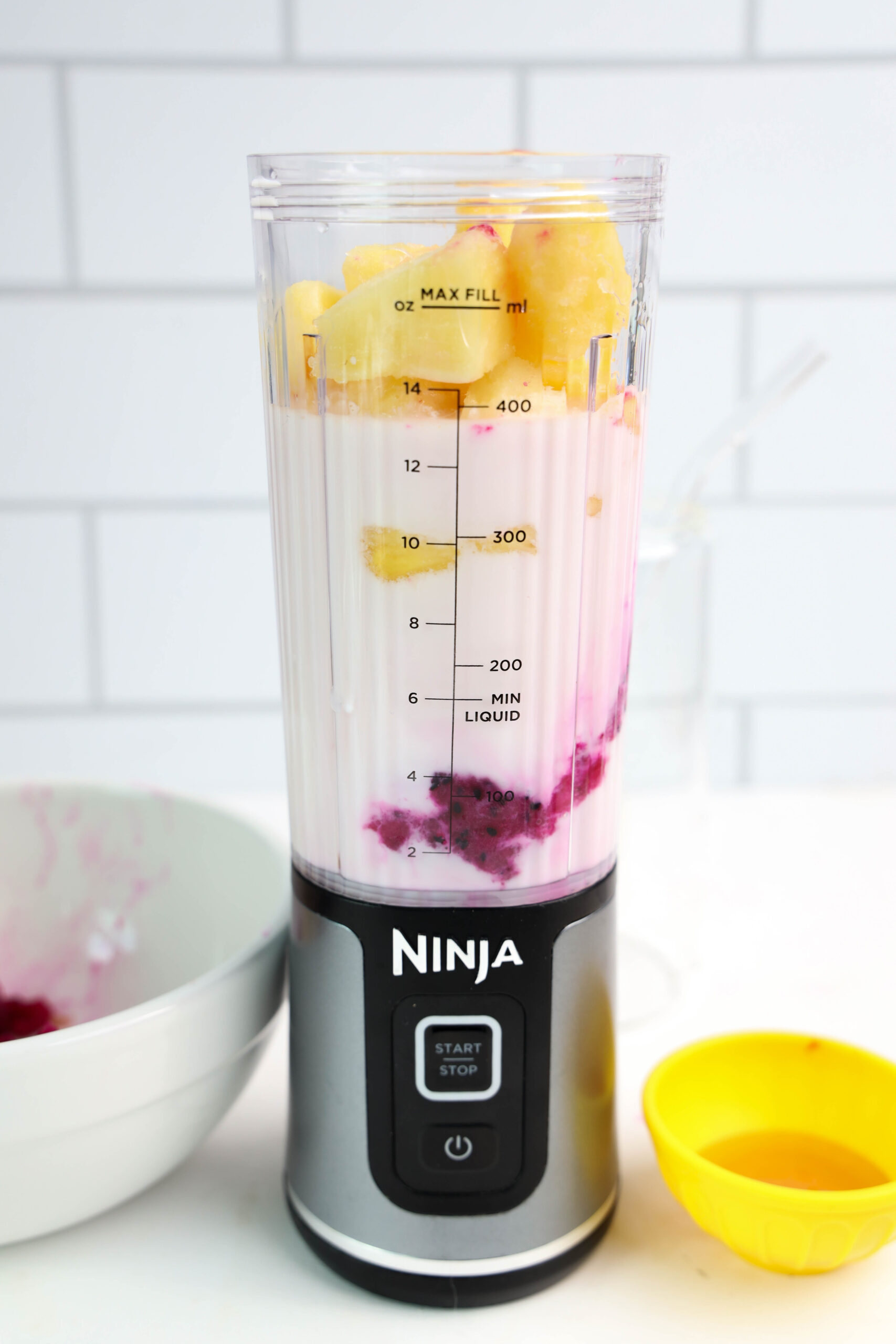 Frozen dragonfruit and pineapple added to milk in a personal blender.