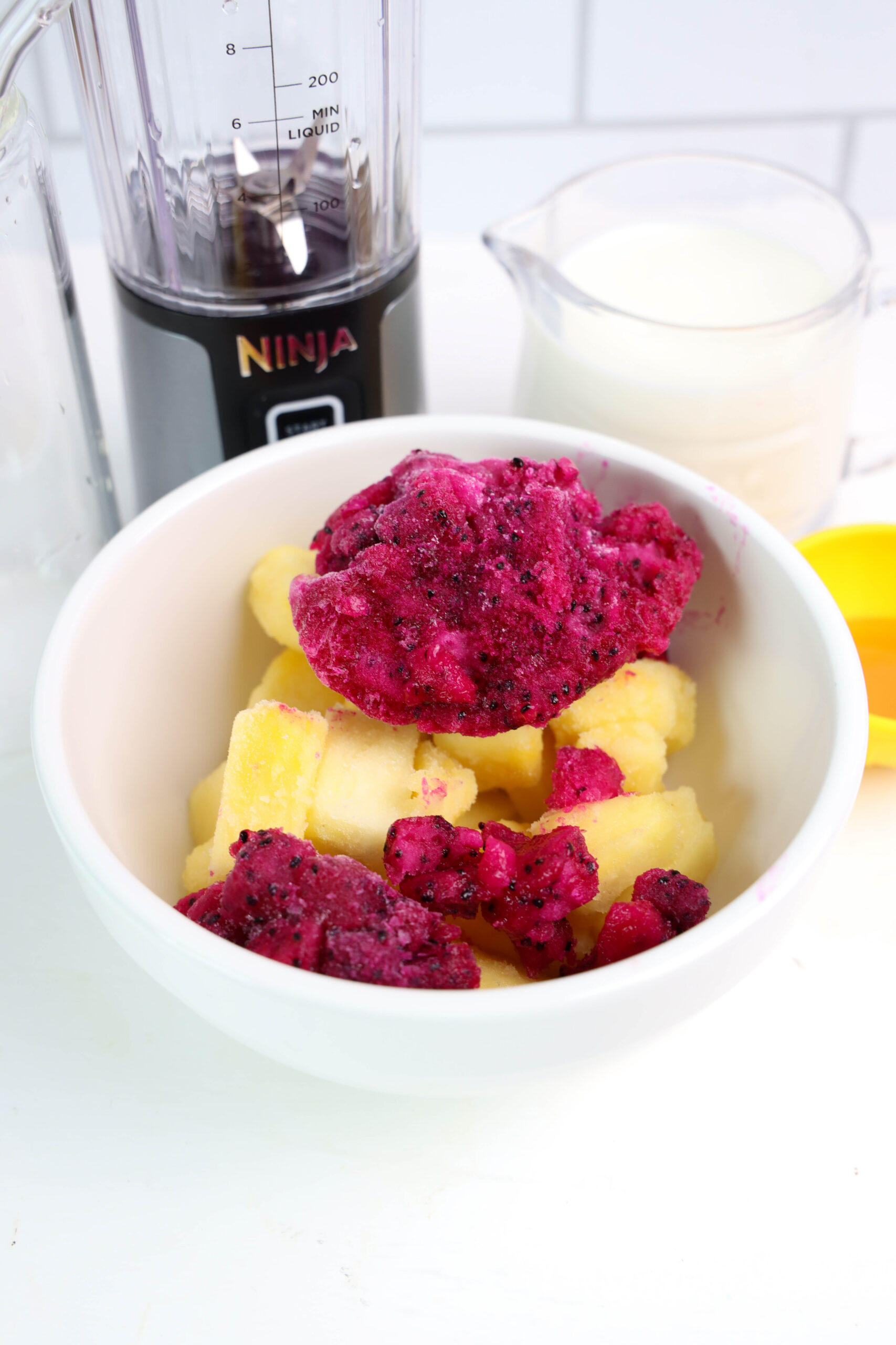 Frozen dragonfruit and pineapple with milk, honey, and a personal blender.