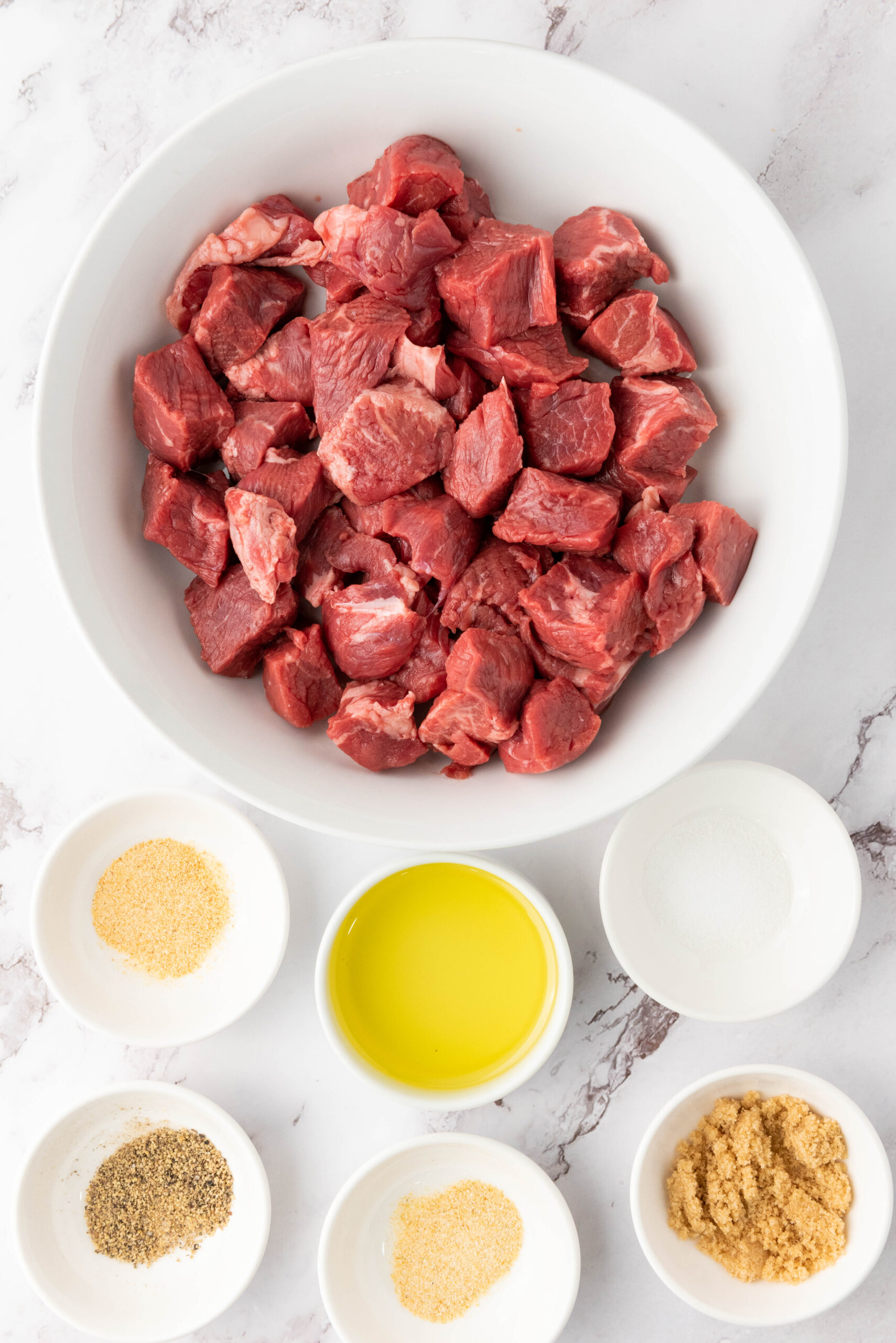 Sirloin steak cut into even bite-sized pieces in a white bowl.