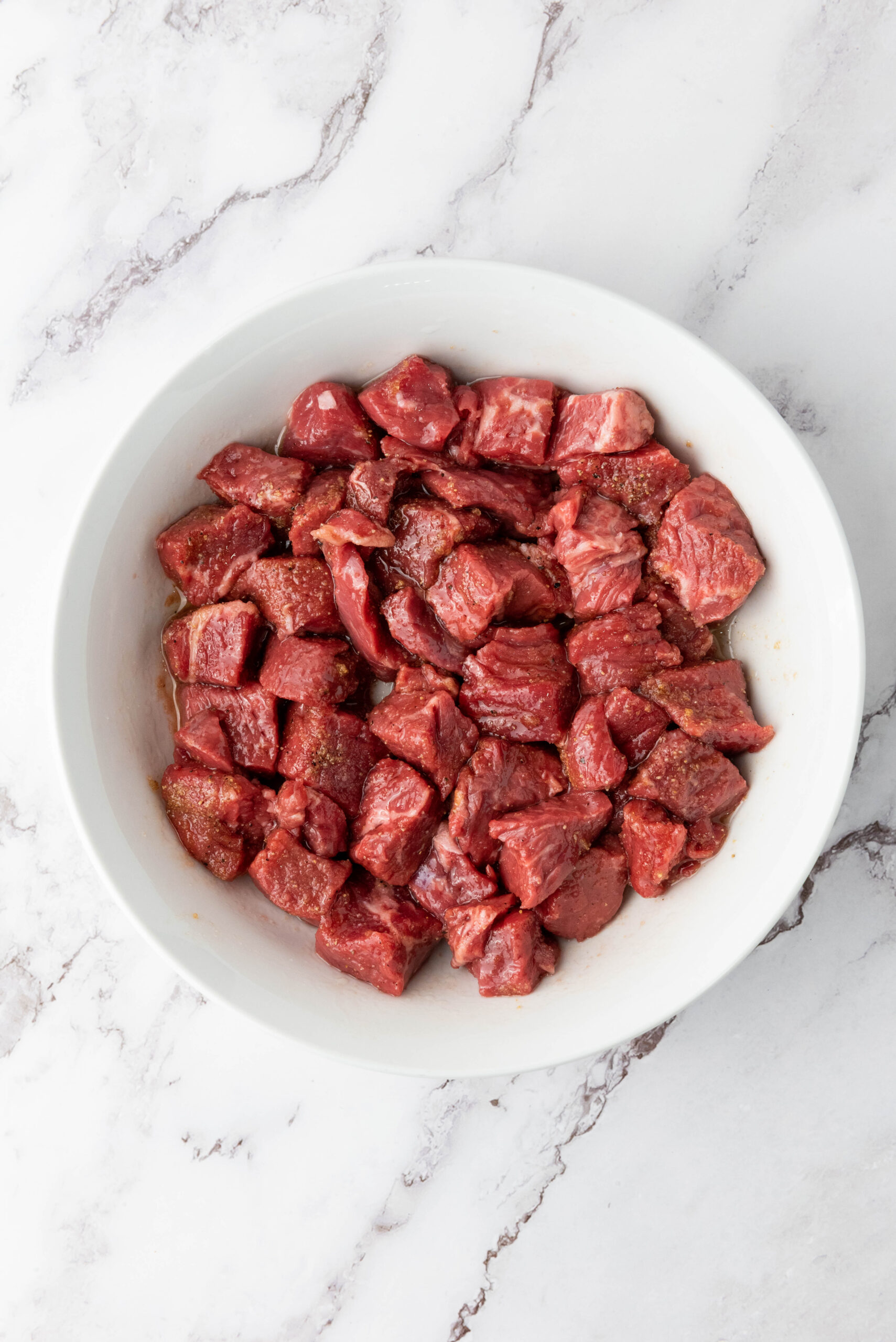 Seasoned and marinated sirloin steak bites in a bowl.