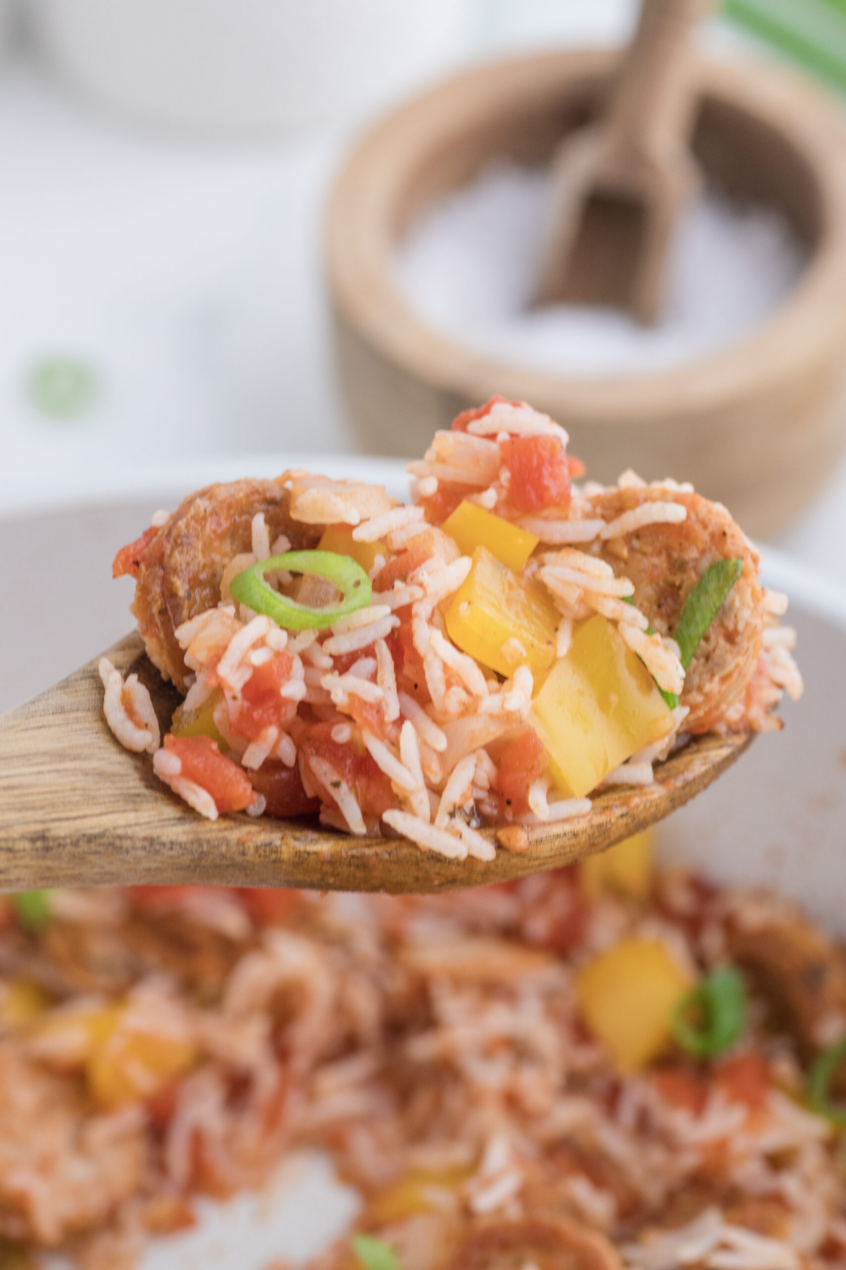 Spoonful of Cajun chicken sausage, rice, tomatoes, yellow pepper, and green onion.