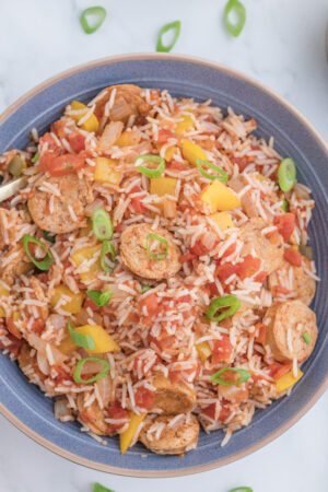 Cajun chicken sausage and rice casserole garnished with sliced green onions in a serving bowl.