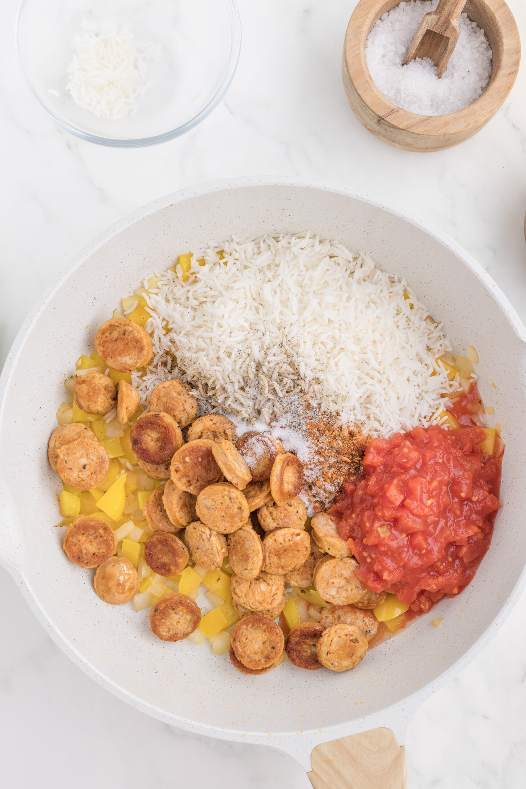 Chicken sausage, rice, tomatoes, vegetables, and Cajun seasonings added to a skillet.