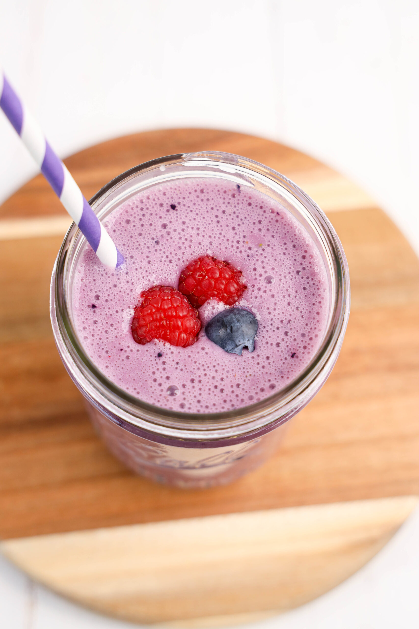 Overhead view of triple berry smoothie topped with raspberries and a blueberry.