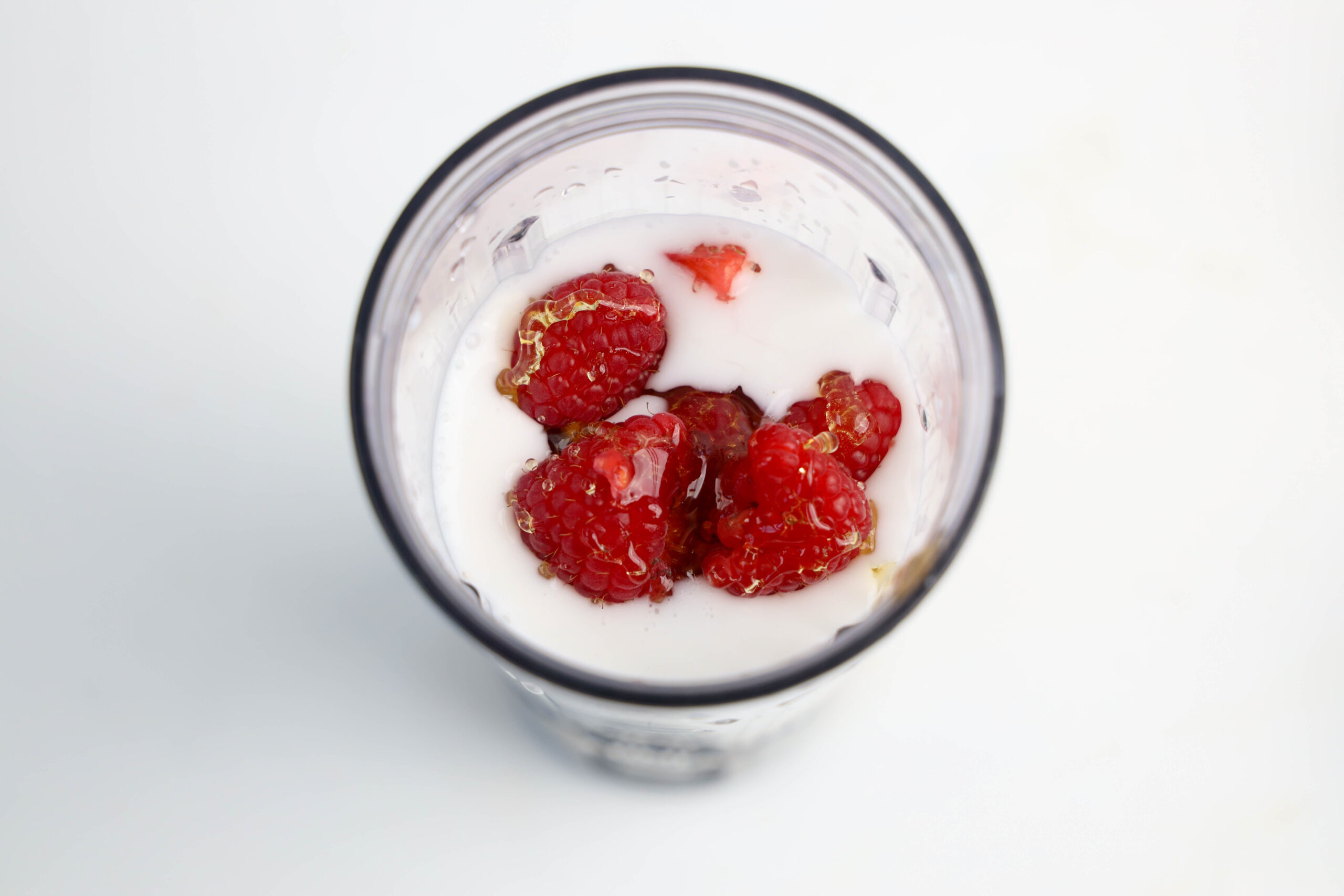 Raspberries and honey added to the berry smoothie ingredients before blending.