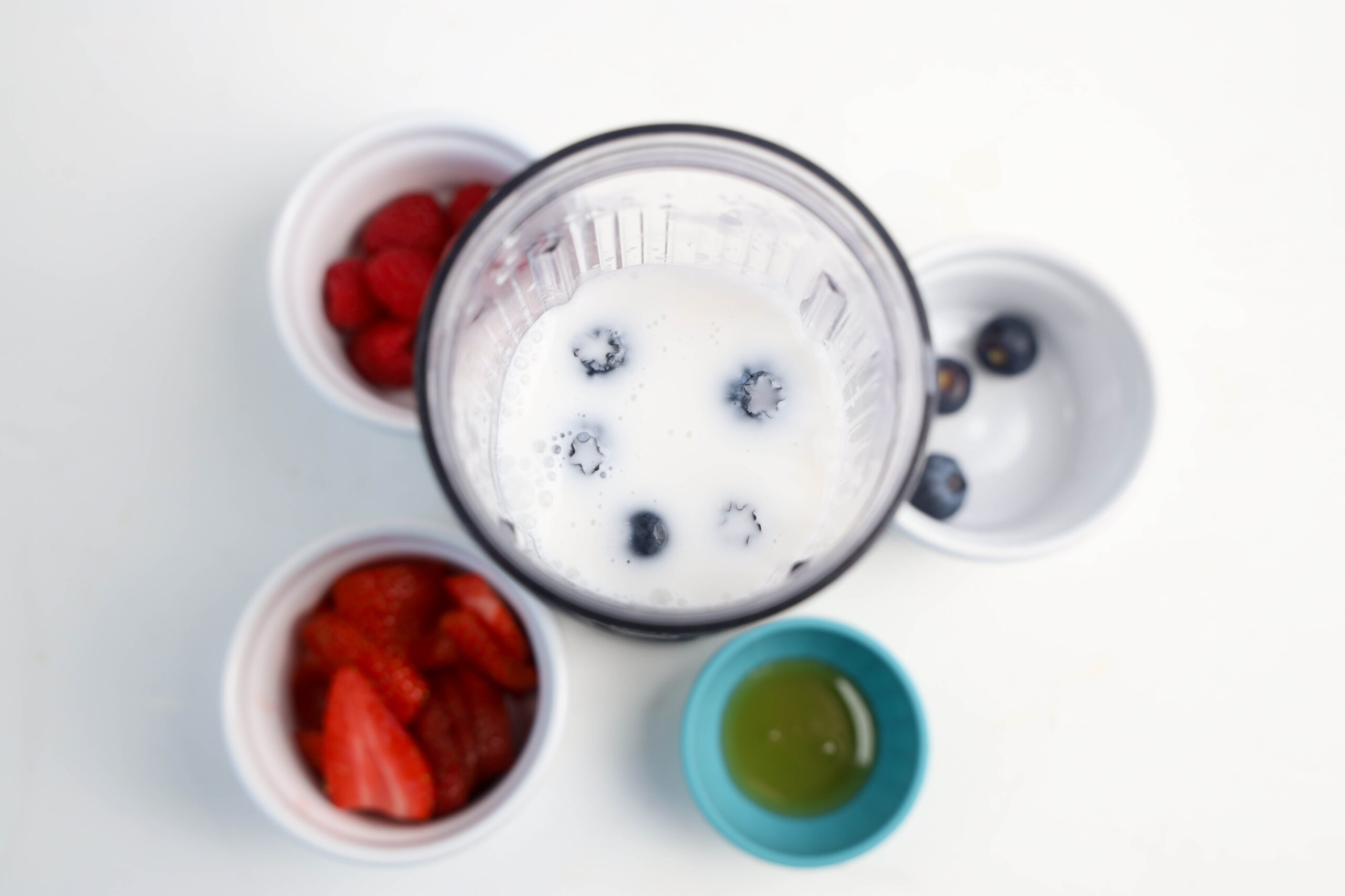 Blueberries added to milk in a personal blender.