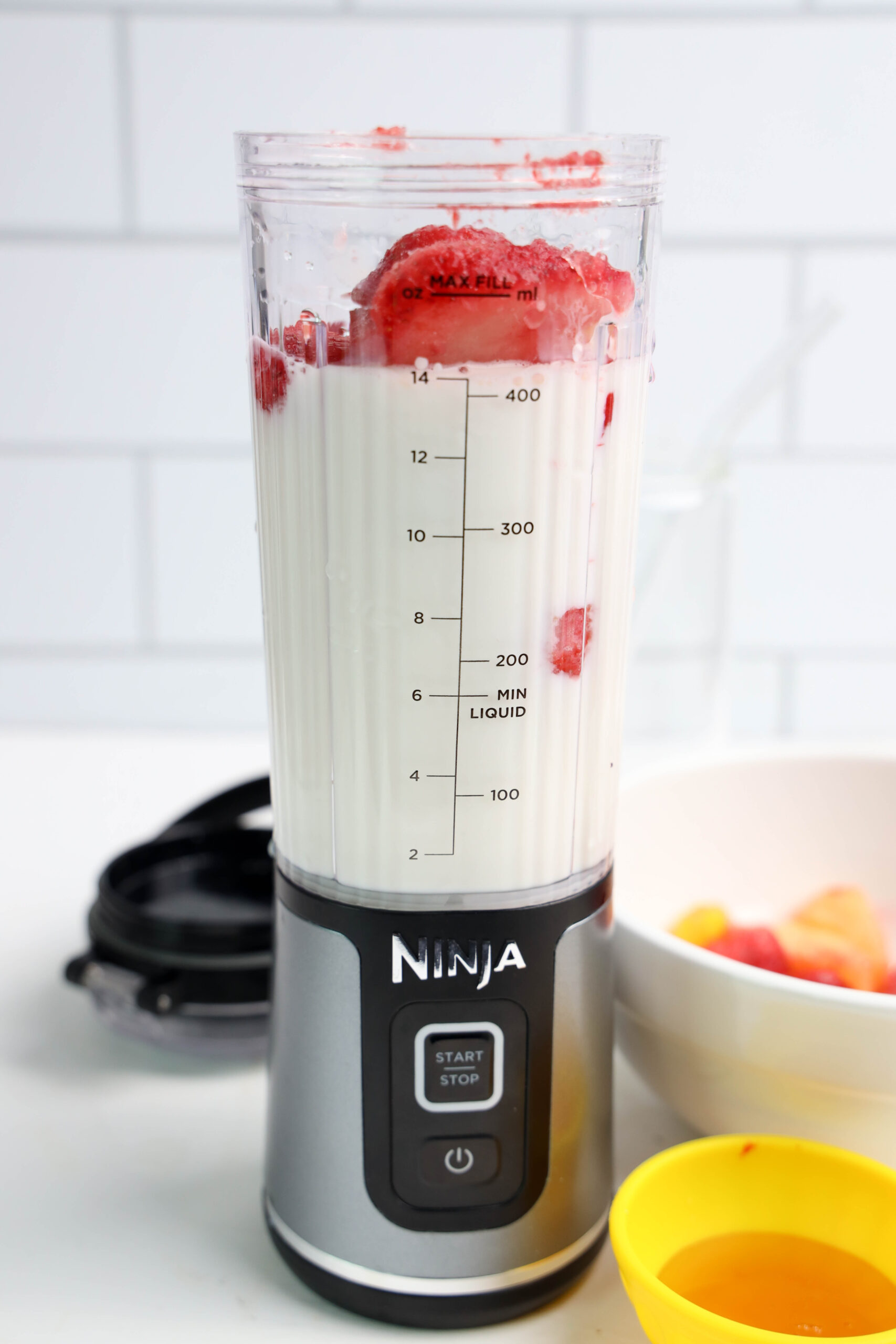 Frozen tropical fruit added on top of milk in a personal blender.