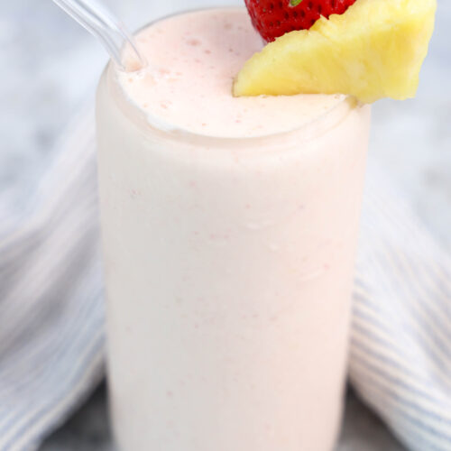 Tropical fruit smoothie garnished with fresh pineapple and a strawberry.